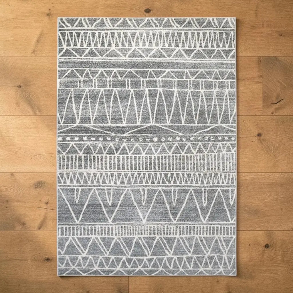 Tapis berbère gris et blanc posé sur un parquet en bois.