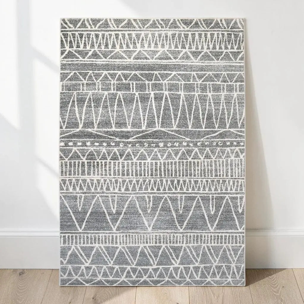 Tapis berbère à motifs géométriques présenté contre un mur clair.