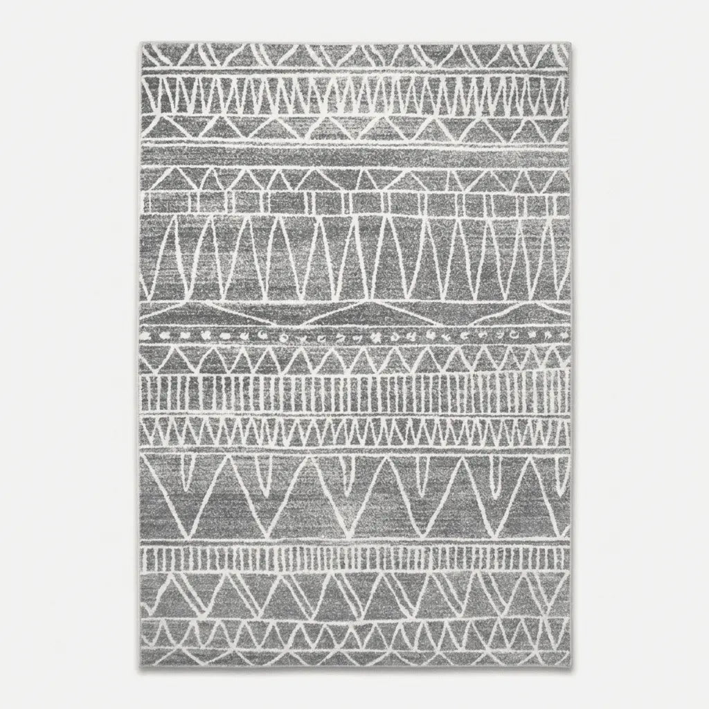 Tapis berbère gris décoré de triangles, zigzags et lignes graphiques blanches.