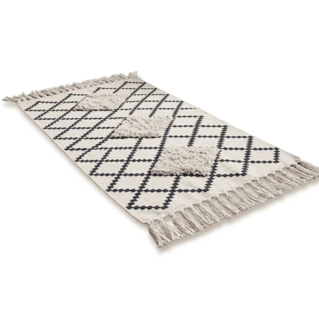 Tapis bohème écru à motifs géométriques noirs, détails en relief et franges.
