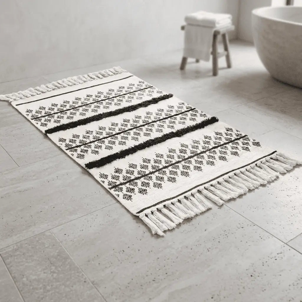 Tapis bohème écru décoré de motifs berbères noirs et de bandes horizontales épaisses au bord d'une baignoire.