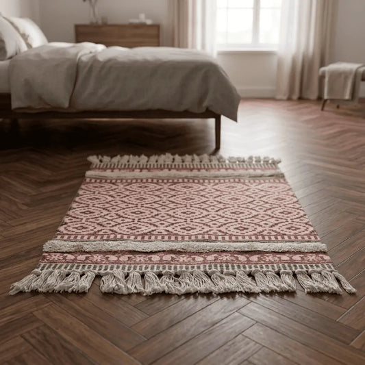Tapis bohème ILYANA placé au pied d’un lit dans une chambre élégante.