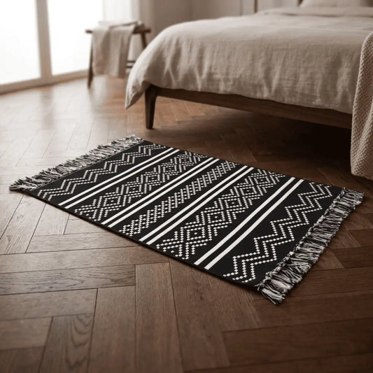Tapis bohème ZAYNA placé au pied d’un lit sur un parquet en bois.