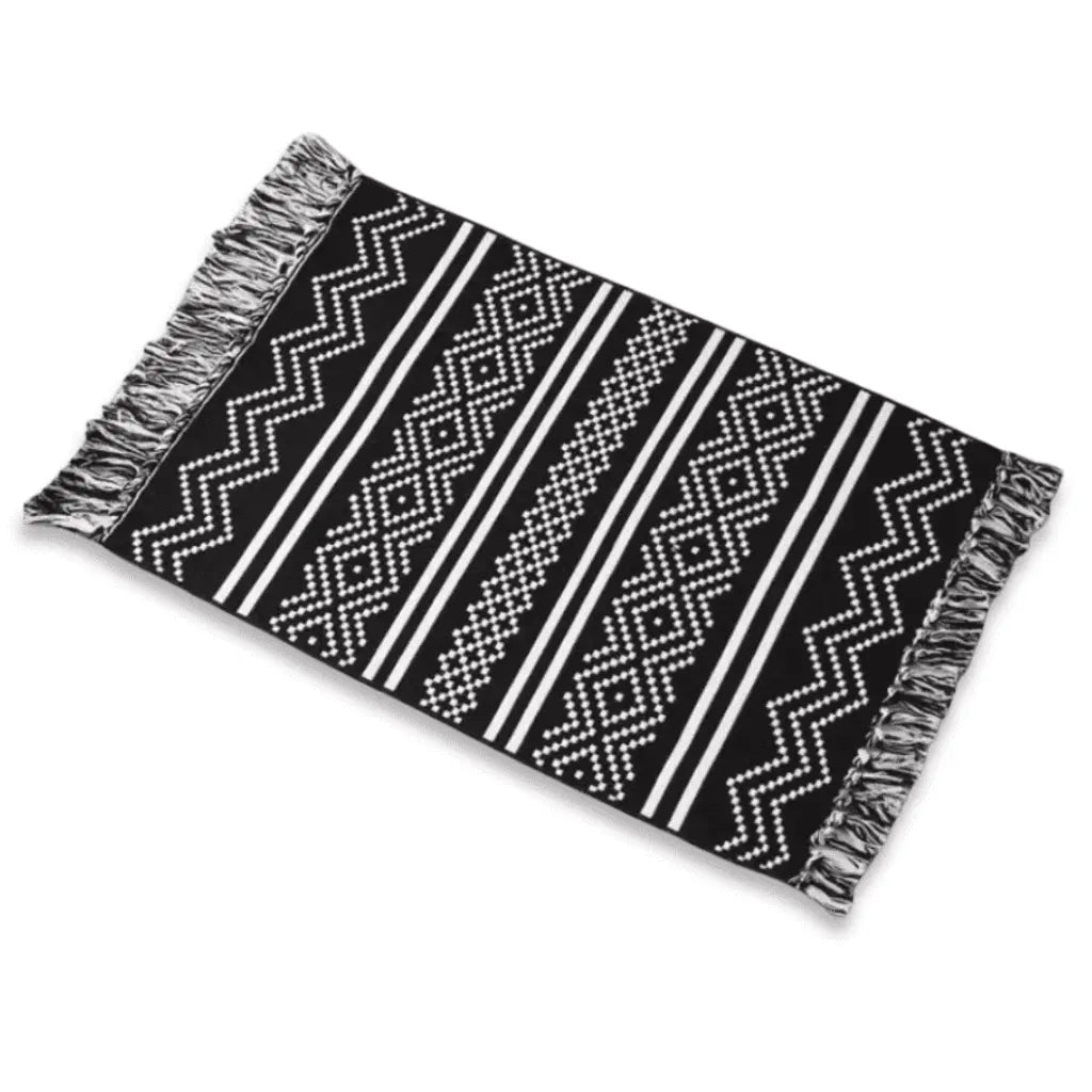 Tapis bohème noir et blanc à motifs géométriques, présenté sur fond blanc.
