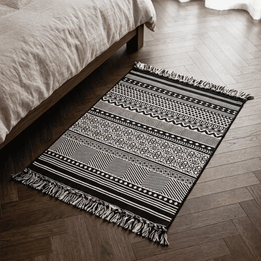Tapis berbère ATLAS placé au pied d’un lit, sur un parquet en bois foncé.