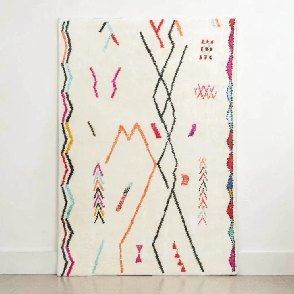 Tapis berbère écru à motifs abstraits présenté contre un mur blanc.