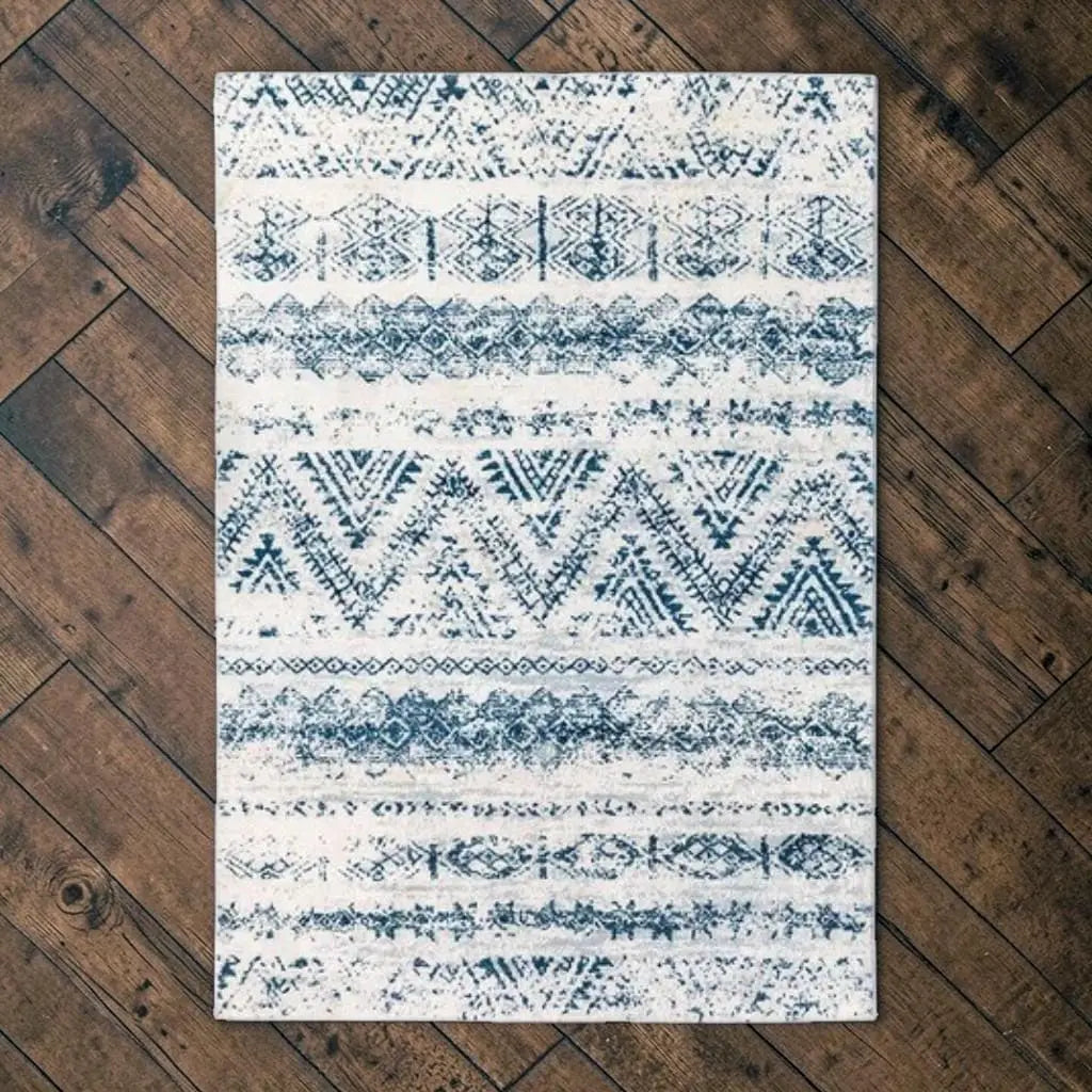 Tapis marocain bleu et blanc posé sur un parquet en bois foncé.