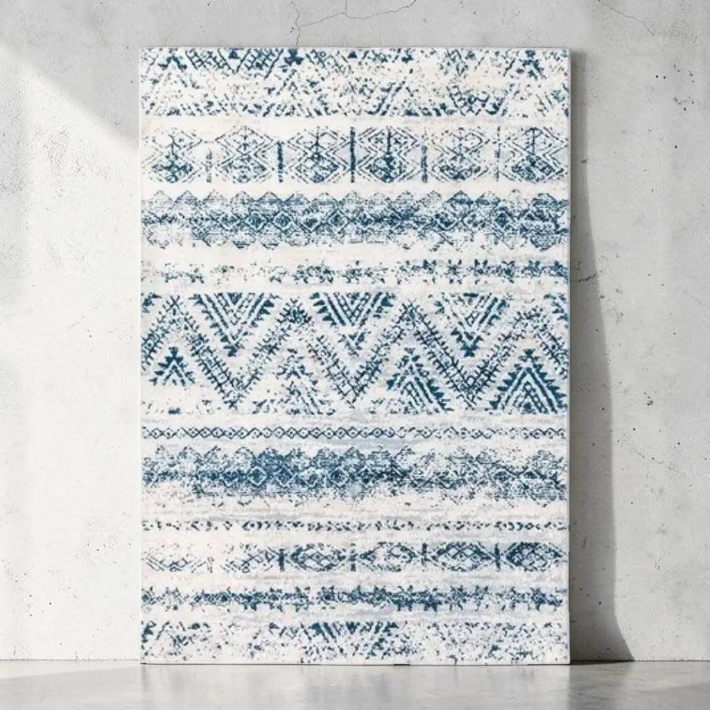 Tapis marocain à motifs berbères bleus présenté contre un mur clair.