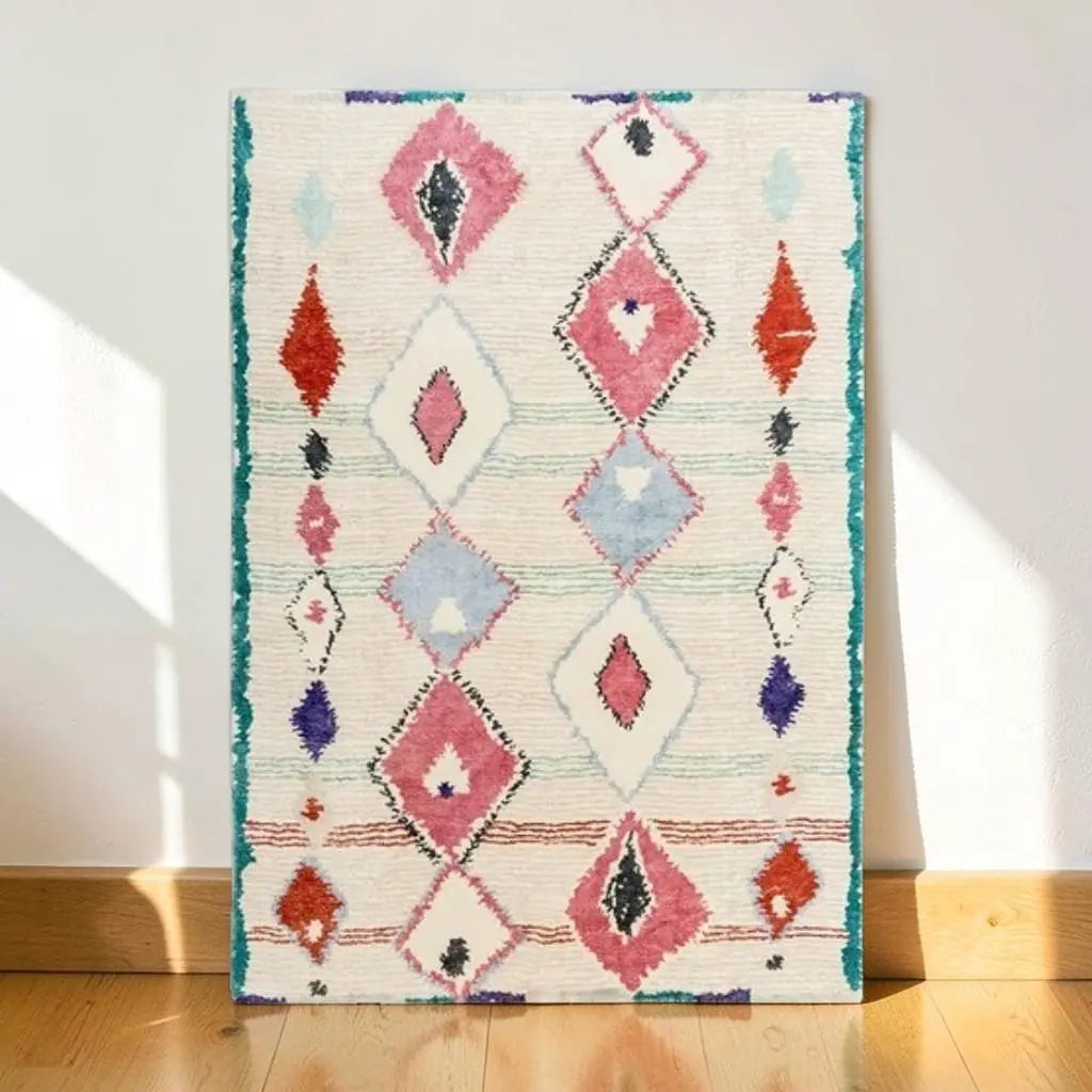 Tapis berbère à motifs géométriques colorés présenté contre un mur clair.