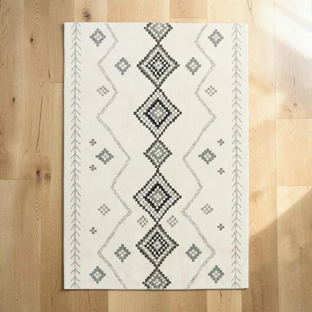 Tapis berbère posé sur un parquet en bois clair, avec motifs géométriques écrus et gris.